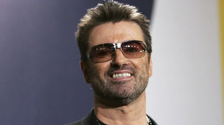 George Michael souriant avec des lunettes de soleil