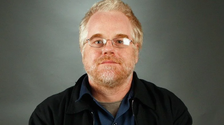 Philip Seymour Hoffman regardant l'appareil photo avec la tête légèrement inclinée