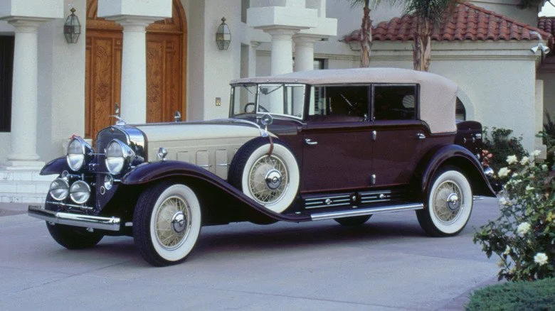 Une photo moderne d'une Cadillac V16 de 1932 devant un manoir