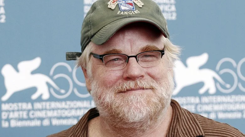 Philip Seymour Hoffman souriant en casquette de baseball