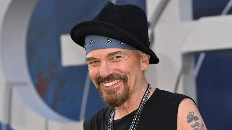 Billy Bob Thornton souriant avec un chapeau noir et une barbichette