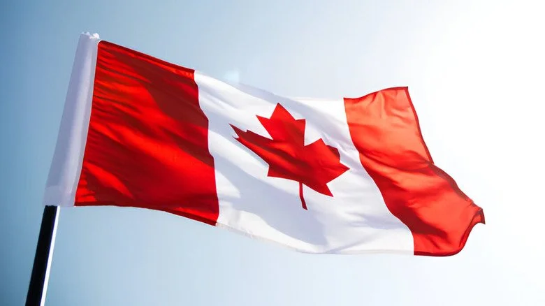 Drapeau canadien flottant au vent sous un ciel ensoleillé