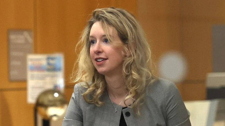 Elizabeth Holmes souriante en costume au tribunal