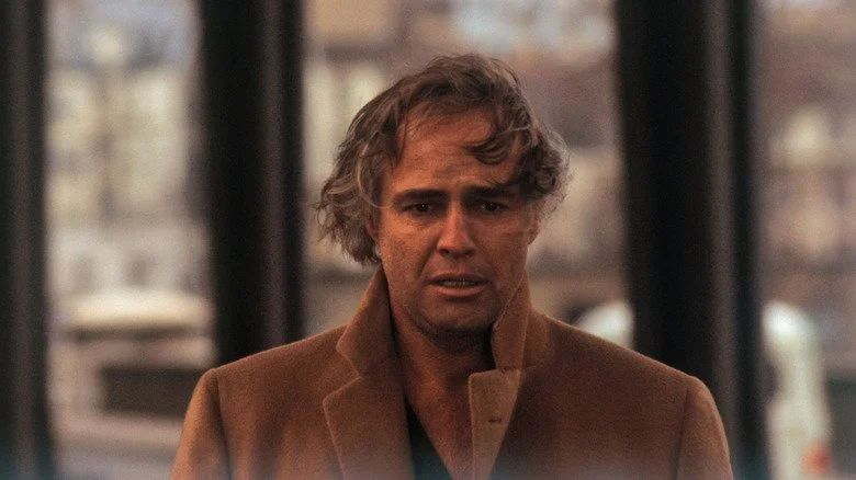 Marlon Brando avec des longs cheveux, portant un manteau beige