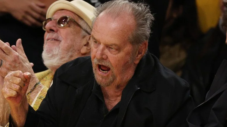 Jack Nicholson criant, poing levé assis lors d'une partie de golf