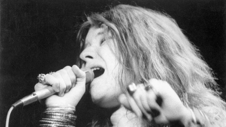 Janis Joplin chantant dans un micro avec plusieurs bracelets