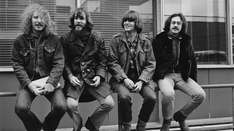 Les membres de Creedence Clearwater Revival assis ensemble sur une rambarde