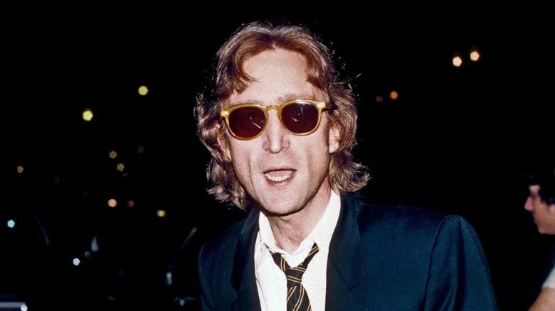 John Lennon avec la bouche ouverte portant des lunettes de soleil