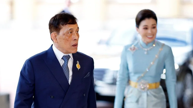 King Vajiralongkorn en costume bleu avec la reine souriante lors d'un événement