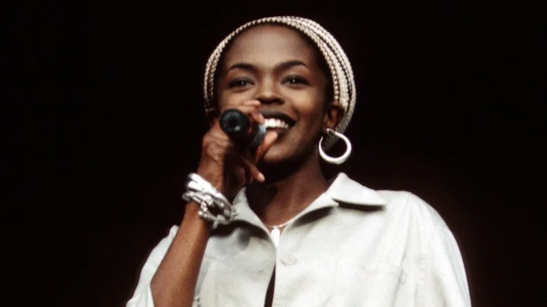Lauryn Hill chantant sur scène et souriant dans les années 90