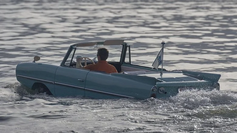Un homme conduisant une Amphicar sur un plan d'eau