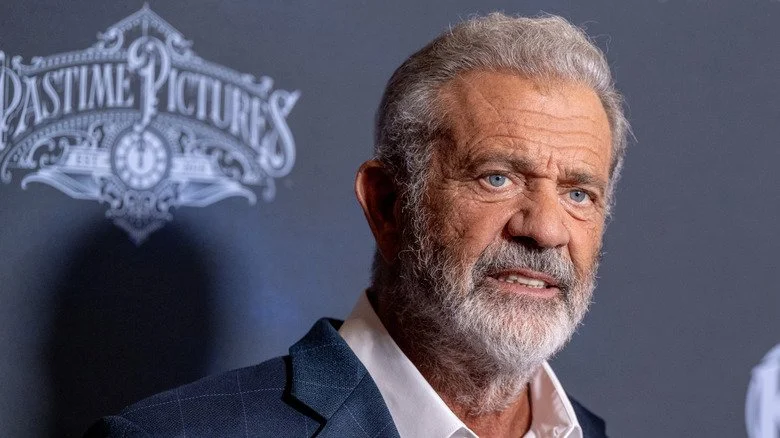 Mel Gibson avec une barbe, posant devant un fond gris-bleu