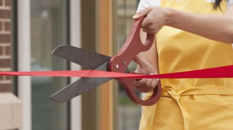Femme coupant un ruban avec des ciseaux surdimensionnés