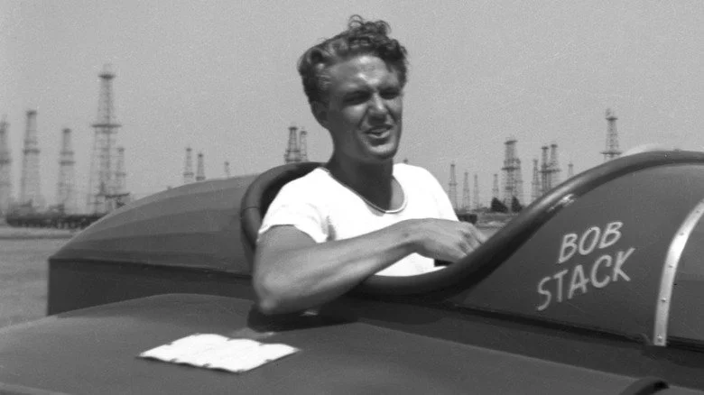Robert Stack squinting and piloting a boat