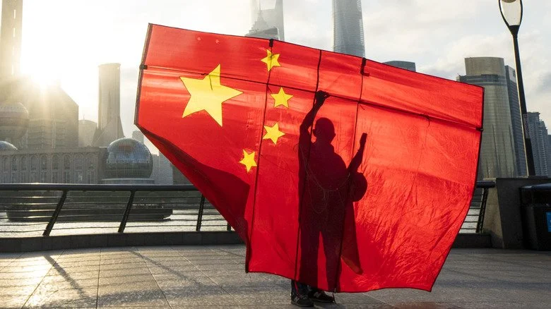 Silhouette d’un homme tenant un drapeau chinois devant une ville