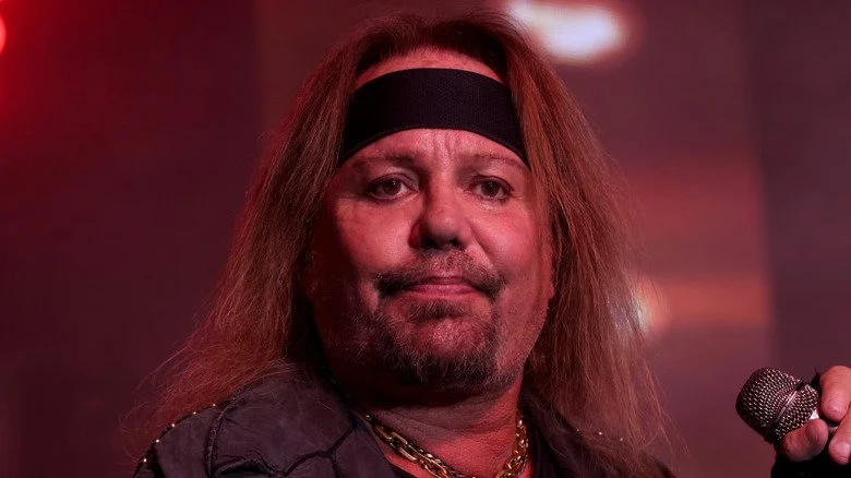 Vince Neil sérieux sur scène tenant un microphone