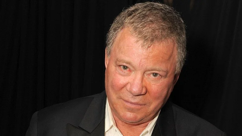 Gros plan de William Shatner devant un rideau noir