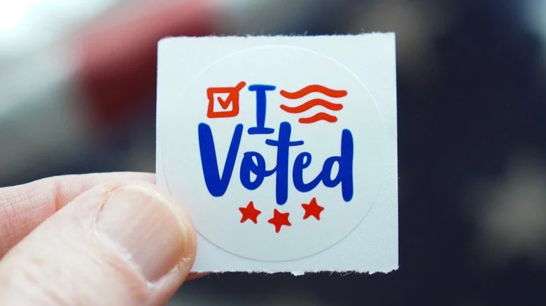 Personne tenant un autocollant 'I voted'