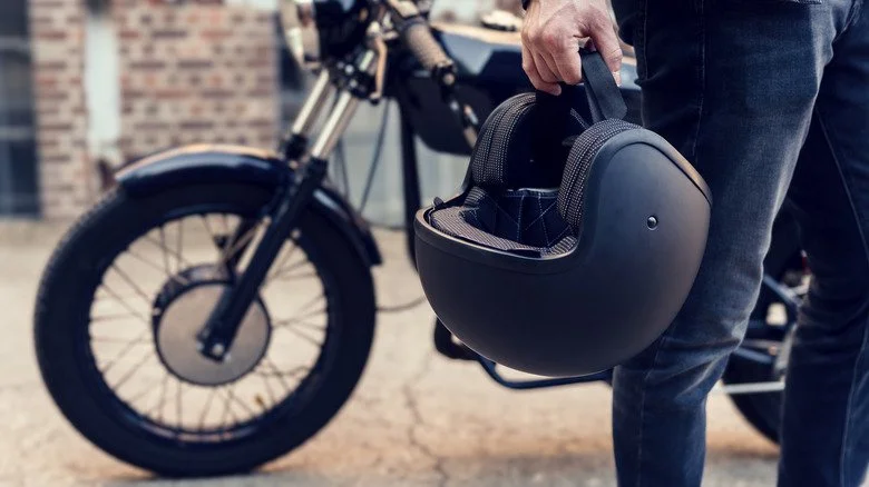 Motard avec sa moto tenant un casque