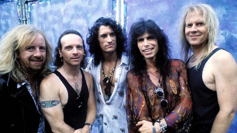 The members of Aerosmith smiling for a photo