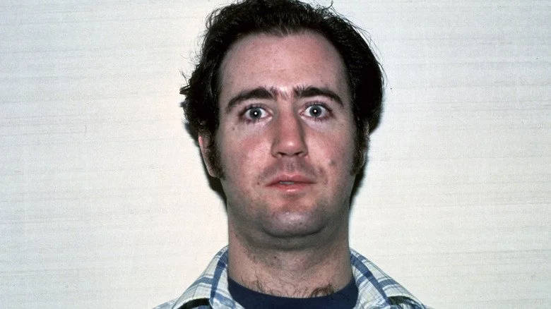 Andy Kaufman regardant devant lui, portant une chemise bleue et blanche