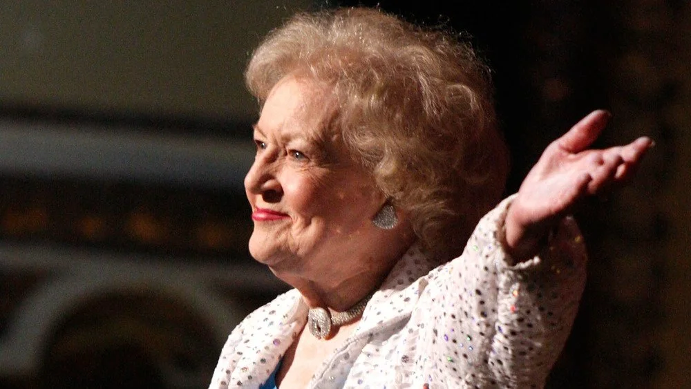 Betty White souriante, main levée
