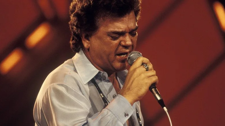 Conway Twitty chantant avec émotion dans un microphone
