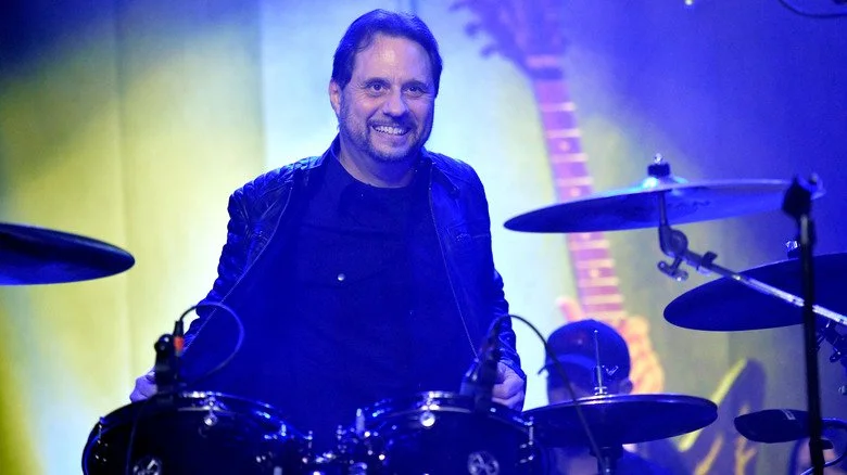 Dave Lombardo assis derrière sa batterie et souriant en 2019