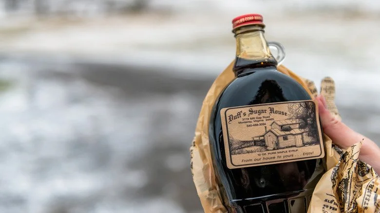 Main tenant une bouteille de sirop d’érable avec petite poignée