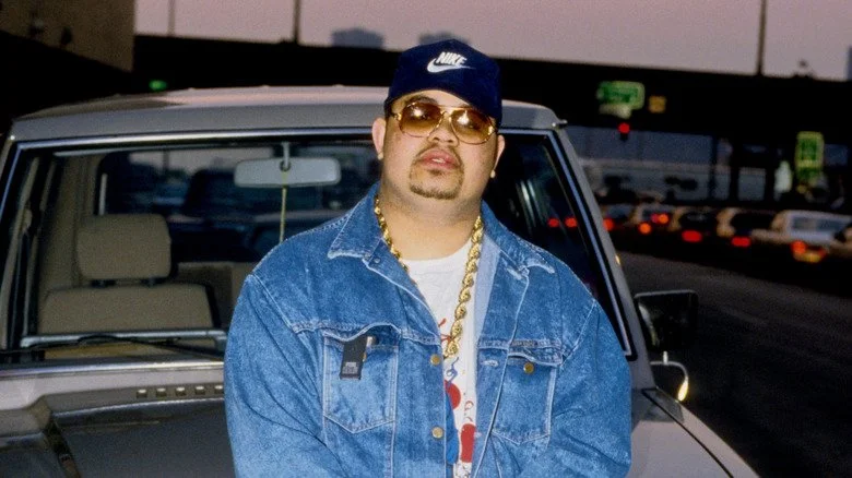 Heavy D in cap posing in front of a car