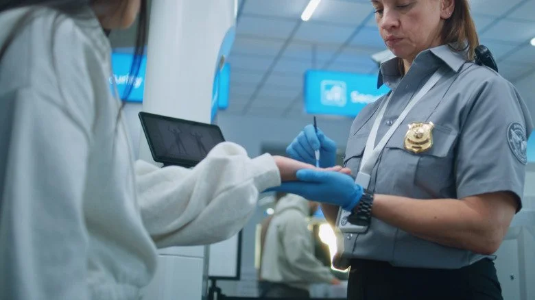 Agent TSA tamponnant les mains d'une passagère