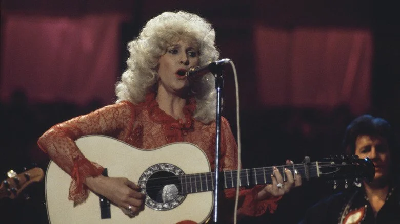 Tammy Wynette assise jouant de la guitare sur scène