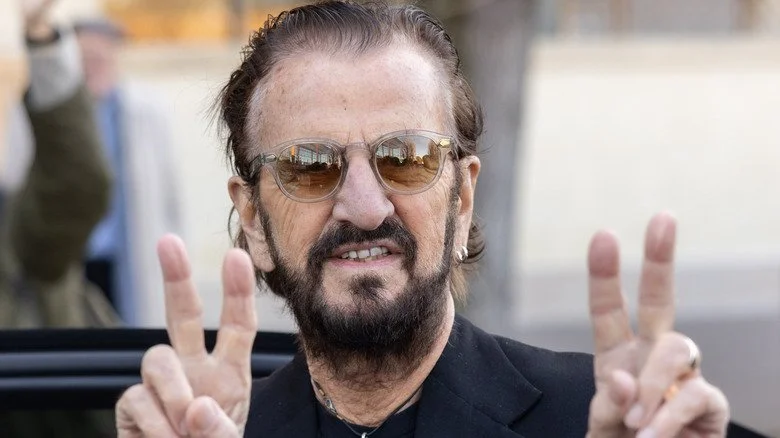 Ringo Starr souriant et faisant le signe de la paix