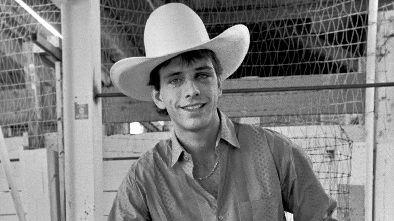 Lane Frost posant avec un grand chapeau dans une grange