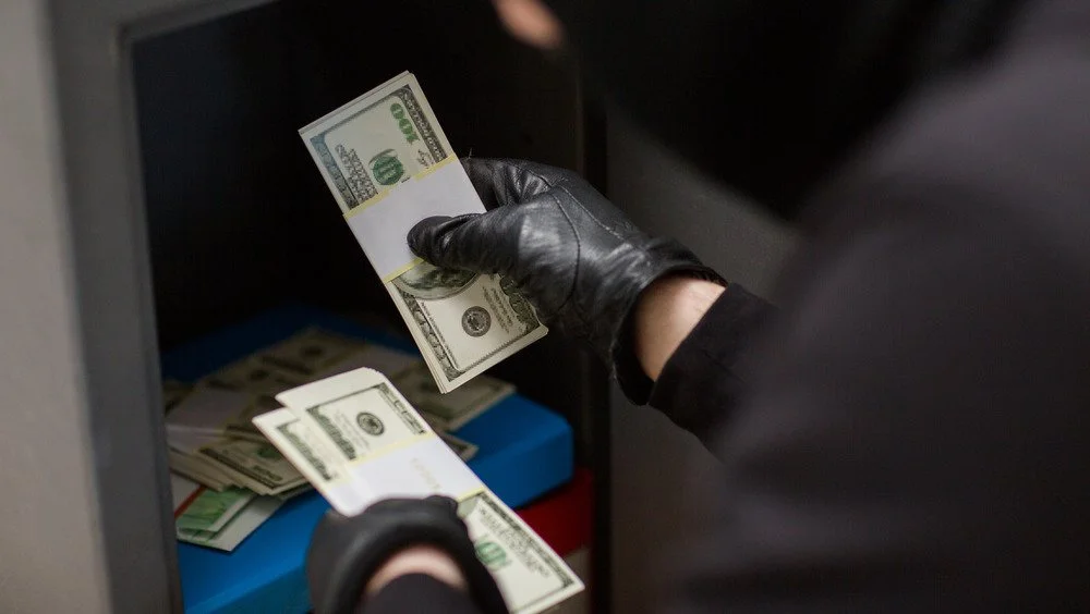 Voleur subtil dérobant de l'argent dans un coffre-fort