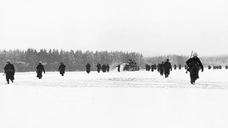 Des troupes américaines marchant à travers un champ enneigé lors de la bataille des Ardennes
