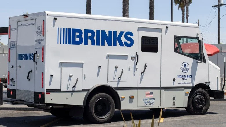 Camion blindé Brink's garé devant des palmiers