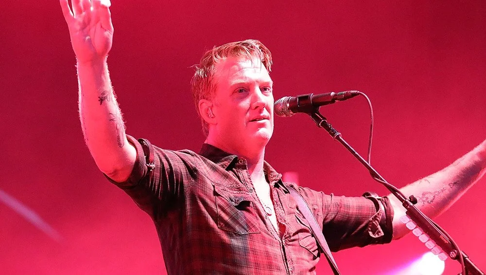 Josh Homme devant un fond rouge