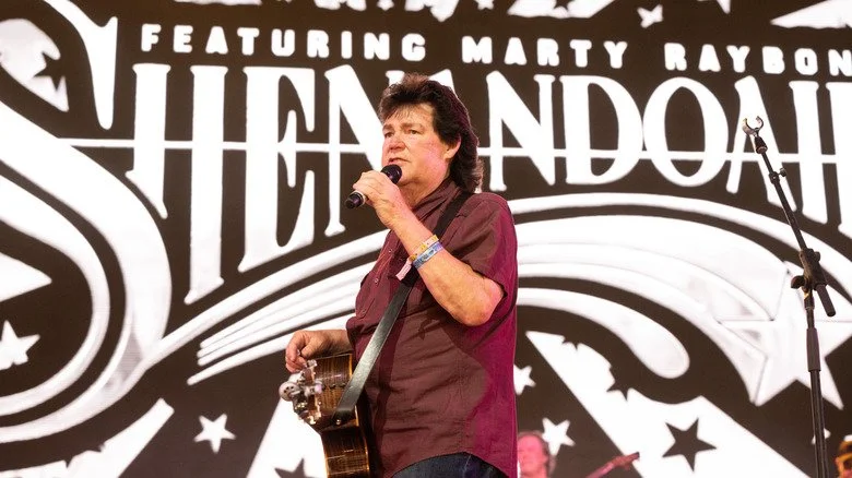 Marty Raybon sur scène devant une banderole portant l'inscription Shenandoah