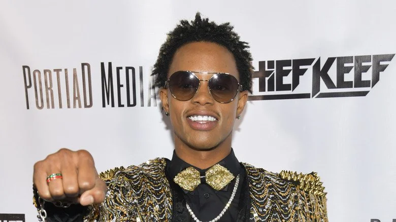 Silento souriant et tendant le poing avec des lunettes de soleil