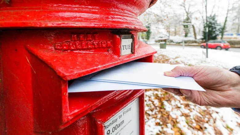 Une personne âgée déposant du courrier