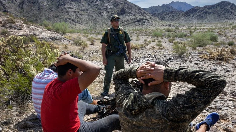 Three migrants being detained after crossing into the U.S. illegally