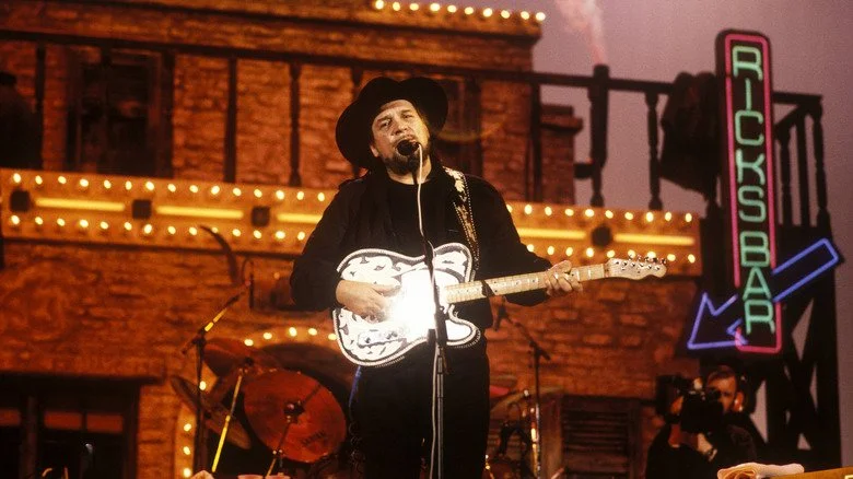 Waylon Jennings en pleine performance devant un décor western élaboré