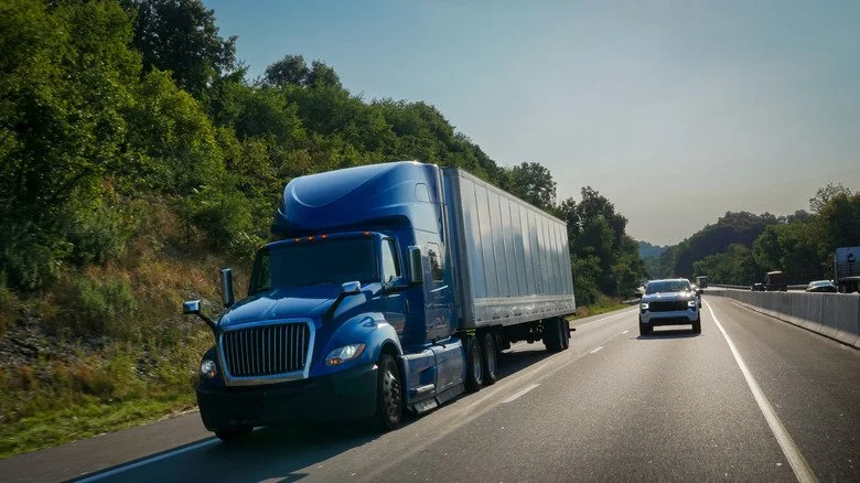 Véhicule circulant à côté d’un camion semi-remorque sur l’autoroute