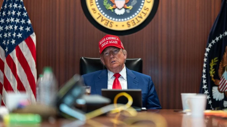 Donald Trump dans son bureau portant une casquette MAGA