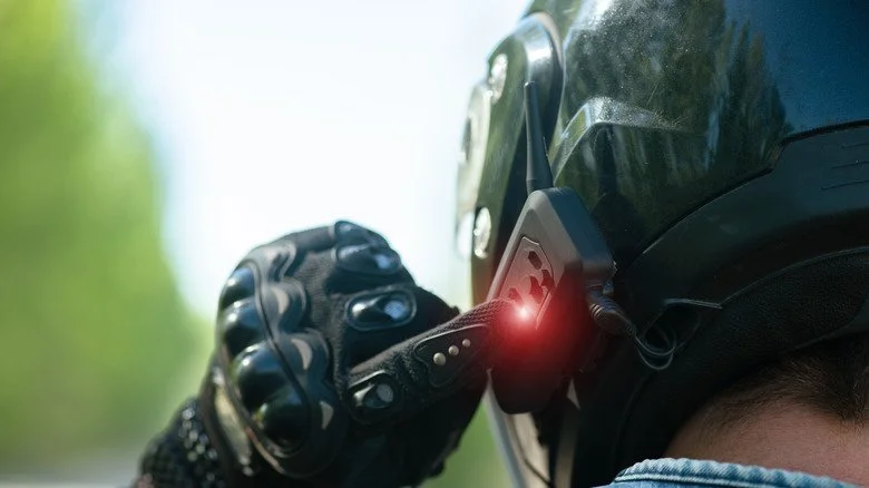 Motard faisant un geste de pouce vers la bouche, indiquant une pause rafraîchissement