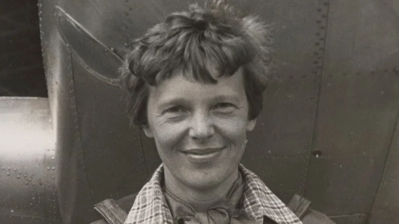 Amelia Earhart souriant devant son avion