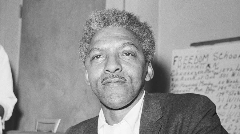 Bayard Rustin assis en costume sombre