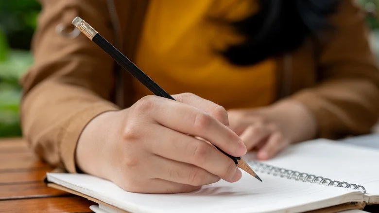 Femme écrivant avec un crayon