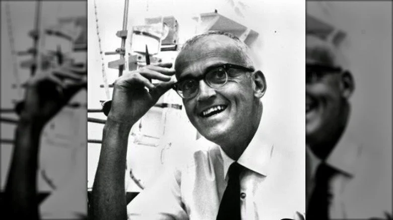 Clair Patterson souriant en chemise blanche et lunettes noires